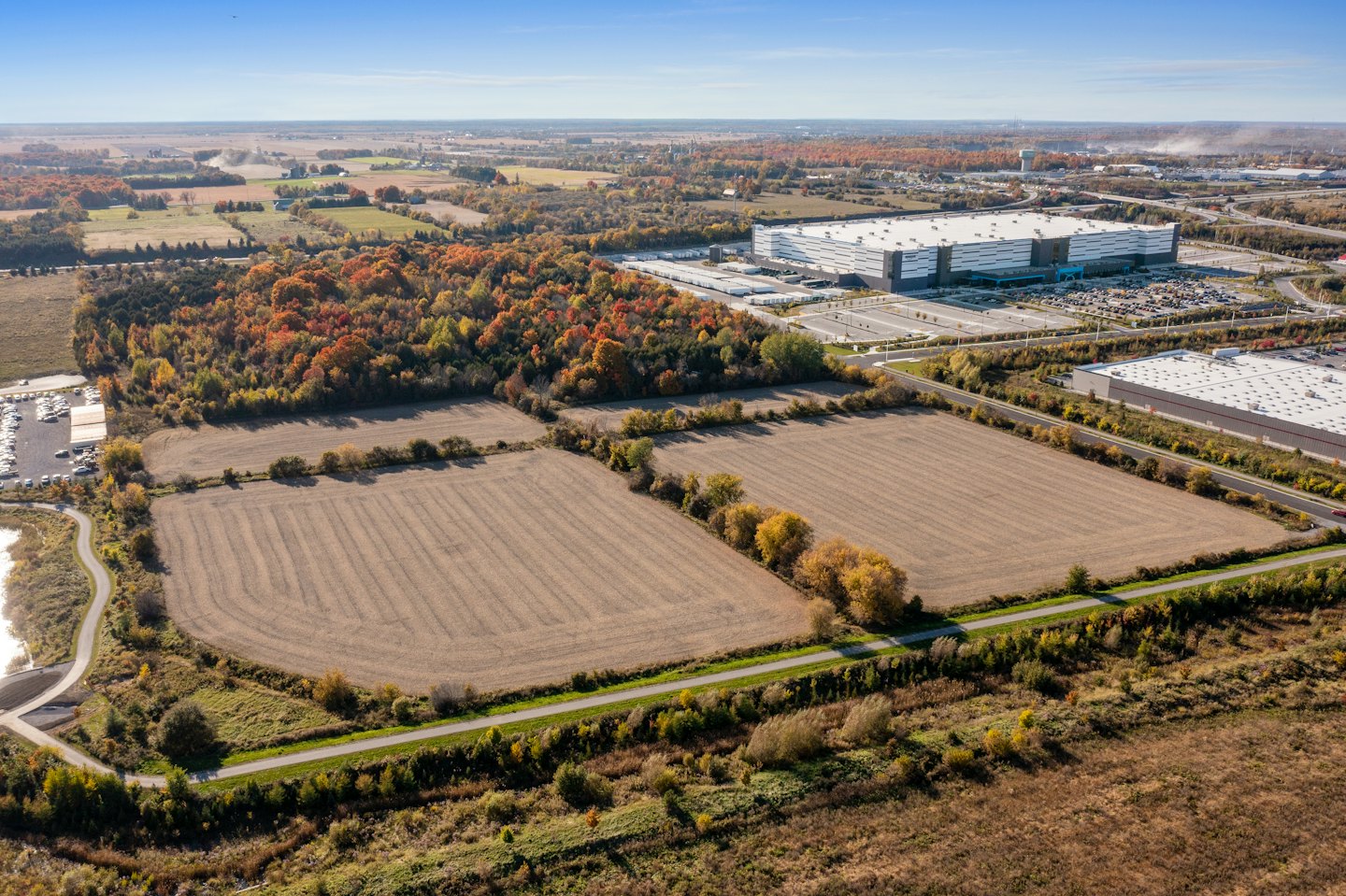 Vista aerea di un complesso industriale adiacente a una foresta e campi autunnali.